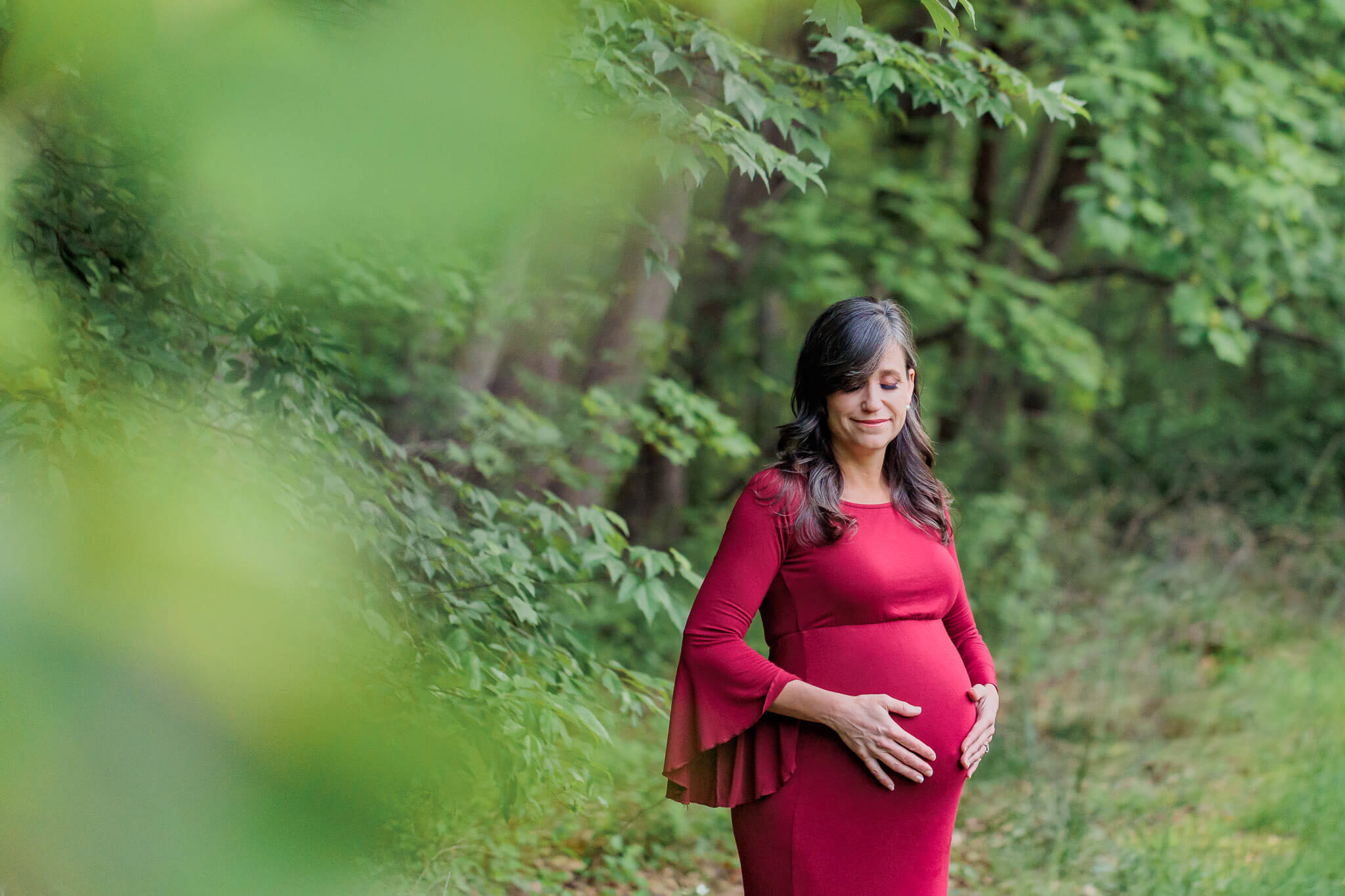 A beautiful mom-to-be wearing a red dress being featured on a blog about maternity photos in Northern Virginia