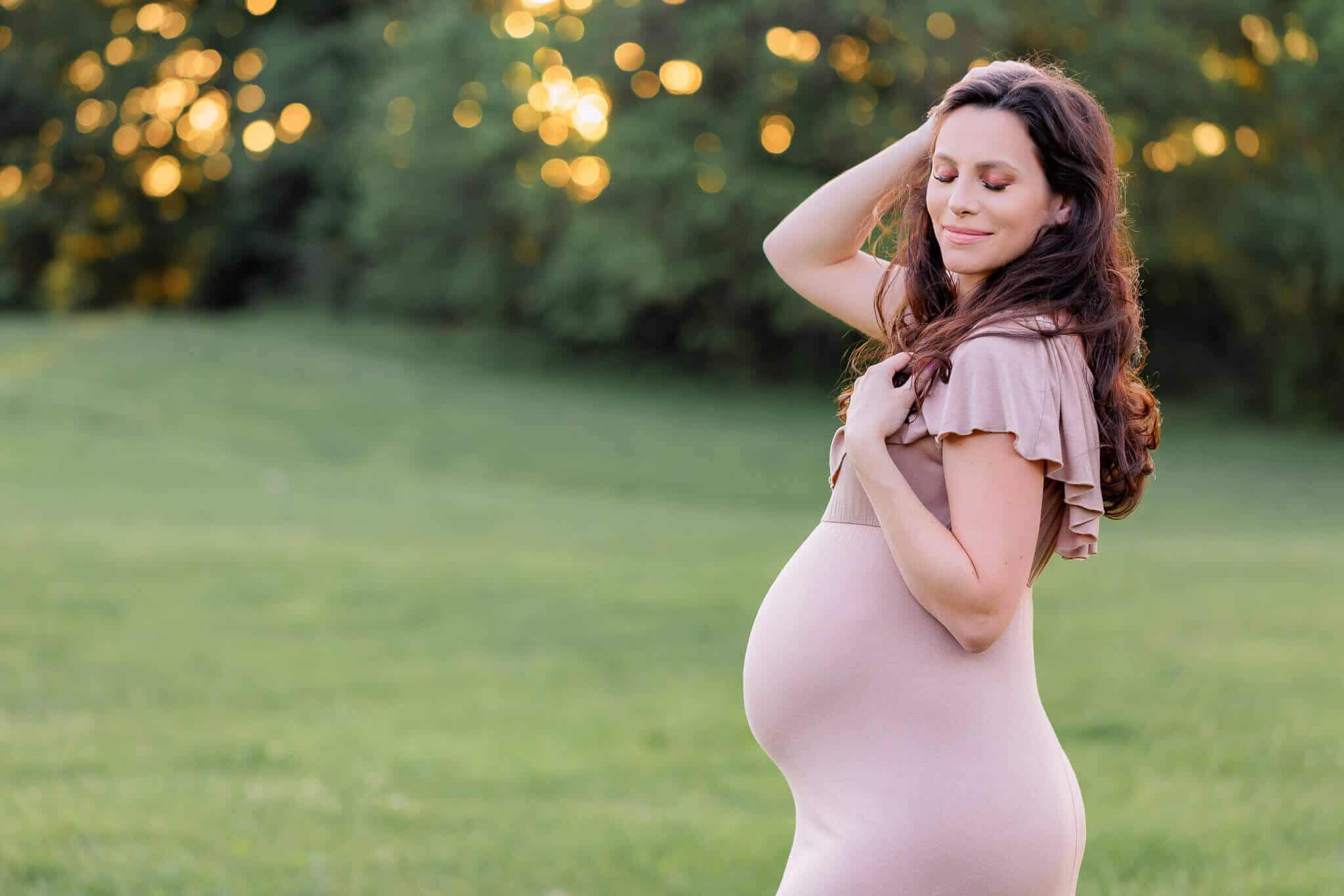 A photo of a beautiful mother-to-be posing in a field at sunset being featured on a blog about Momease.