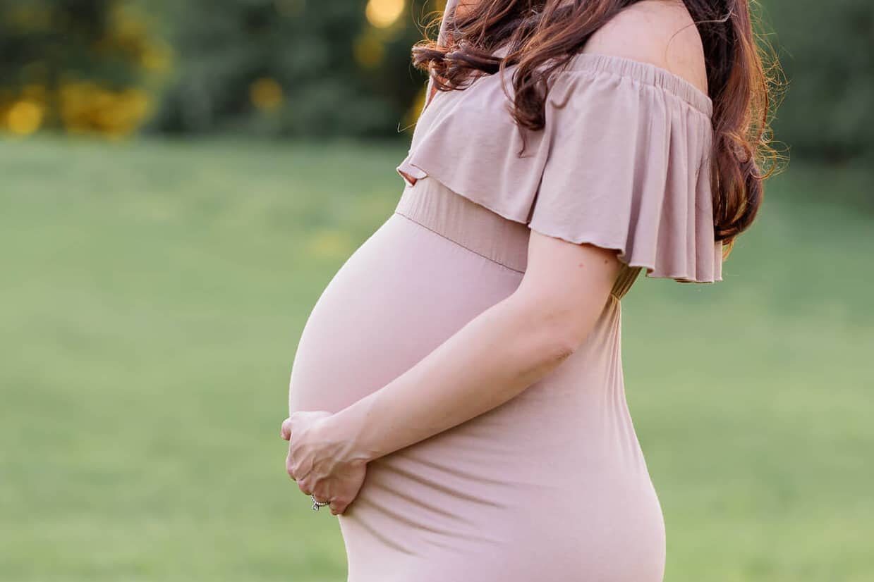 A closeup of a pregnant woman's belly in a tan dress featured on a blog about Capital Women's Care