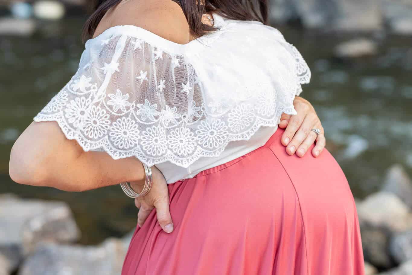 A close-up of a pregnant woman's belly in a white top and terra cotta skirt featured in a blog about Doulas of Northern Virginia.
