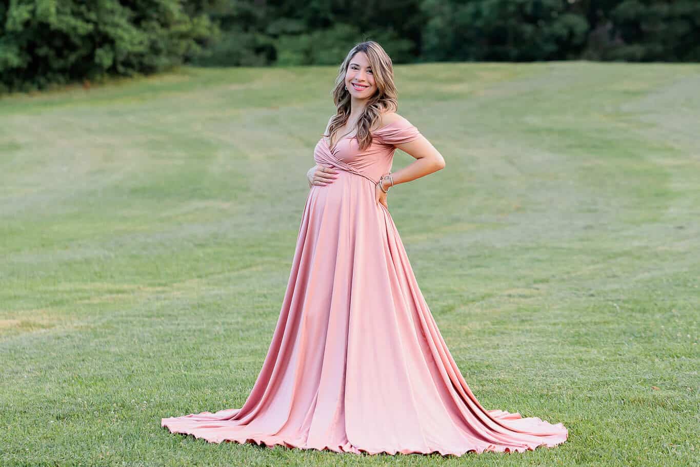 A blog about Fairfax Birth Care featuring a picture of a mother-to-be posing in a green field and wearing a pink dress.