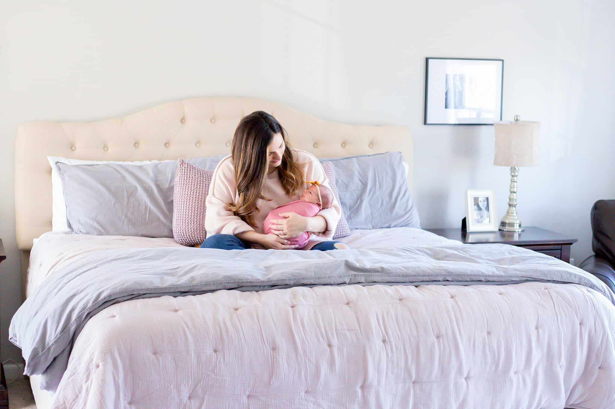 A mom snuggling her newborn in bed featured on a blog about a professional organizer in Northern Virginia.
