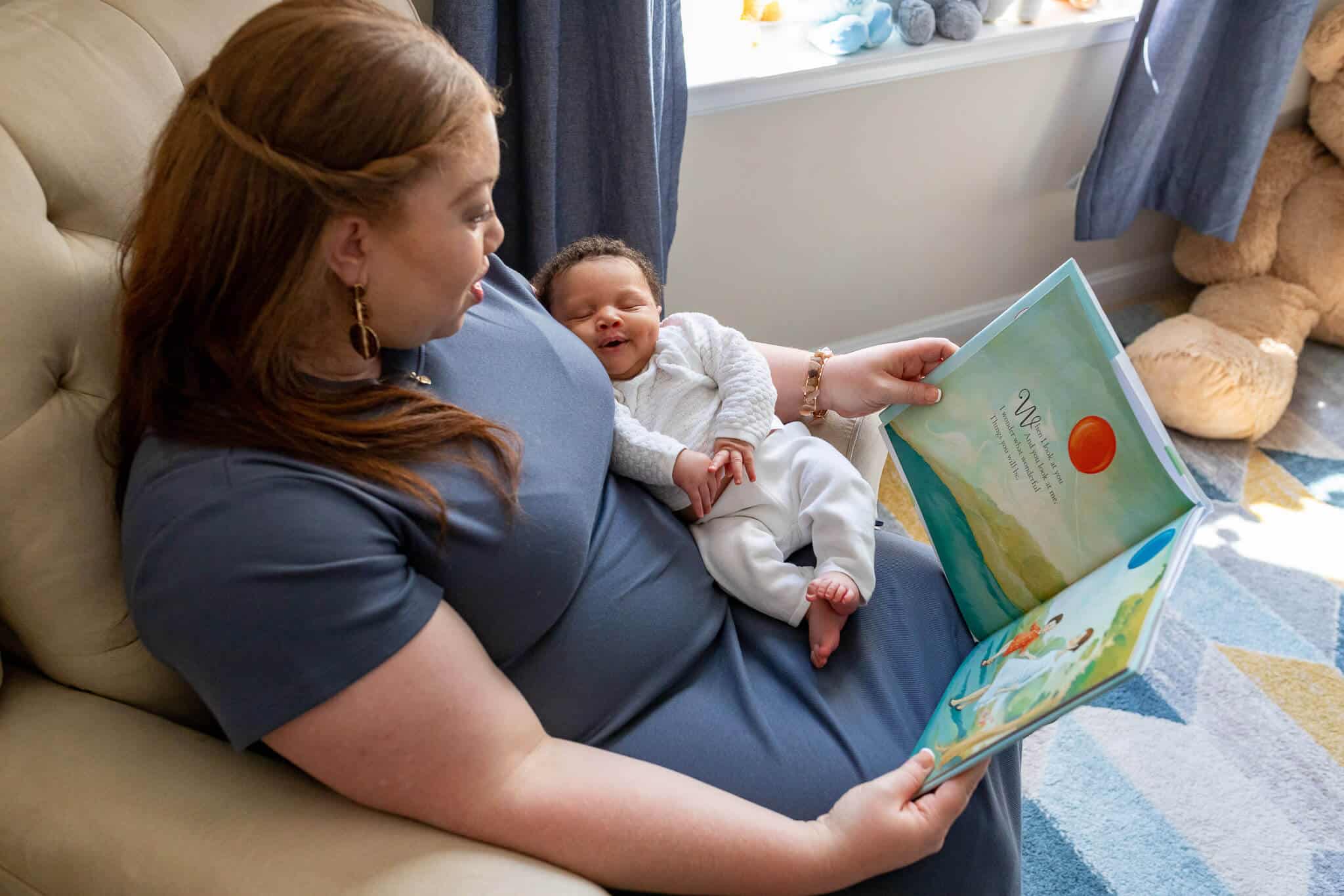 A newborn boy sleeping in his mom's lap while she reads to him featured in a blog about a sleep consultant in Northern Virginia.