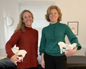 The two female doctors holding pelvis models for their business Transition Physical Therapy.