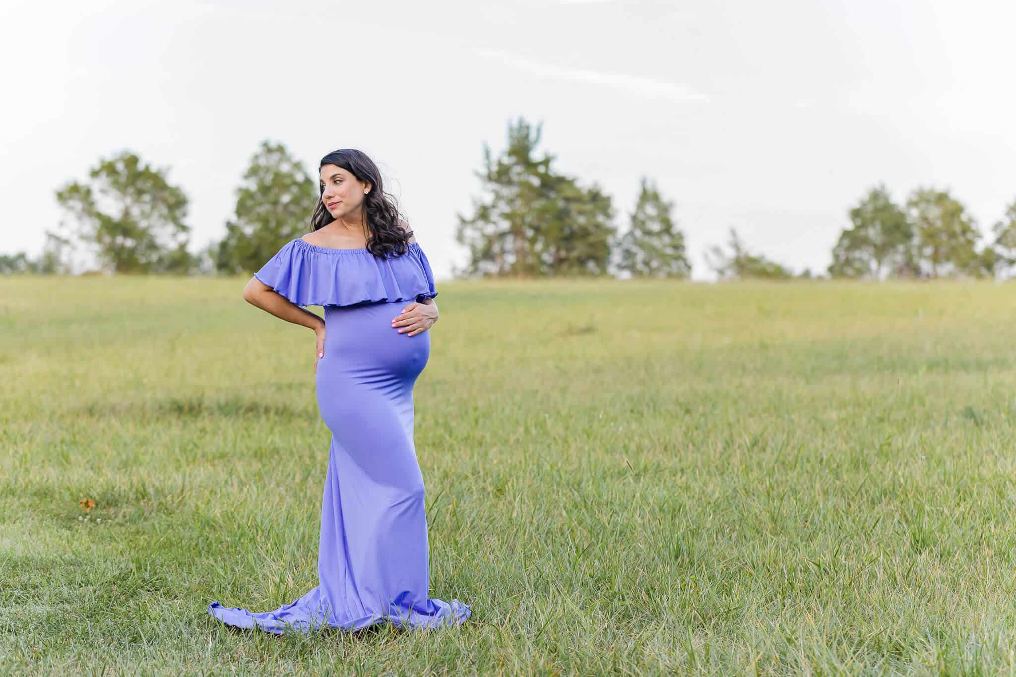 A pregnant woman posing in a green field being featured on a blog about Alexandria yoga studios.