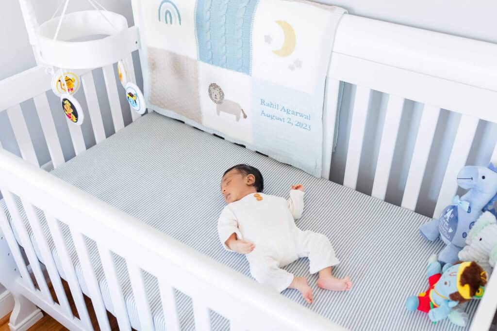 A baby boy sleeping in his crib at his lifestyle newborn session in his home.